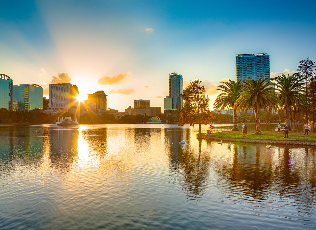 Orlando FL Insurance - Sun Shining Behind Large Corporate Buildings and Palm Trees by the Water